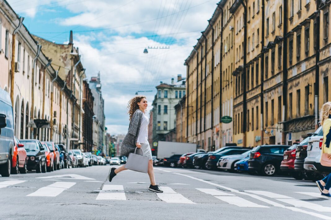 Pewna siebie kobieta przechodzi przez pasy w tętniącym życiem mieście Pewna siebie kobieta przechodzi przez pasy w tętniącym życiem mieście