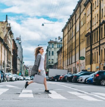 Pewna siebie kobieta przechodzi przez pasy w tętniącym życiem mieście